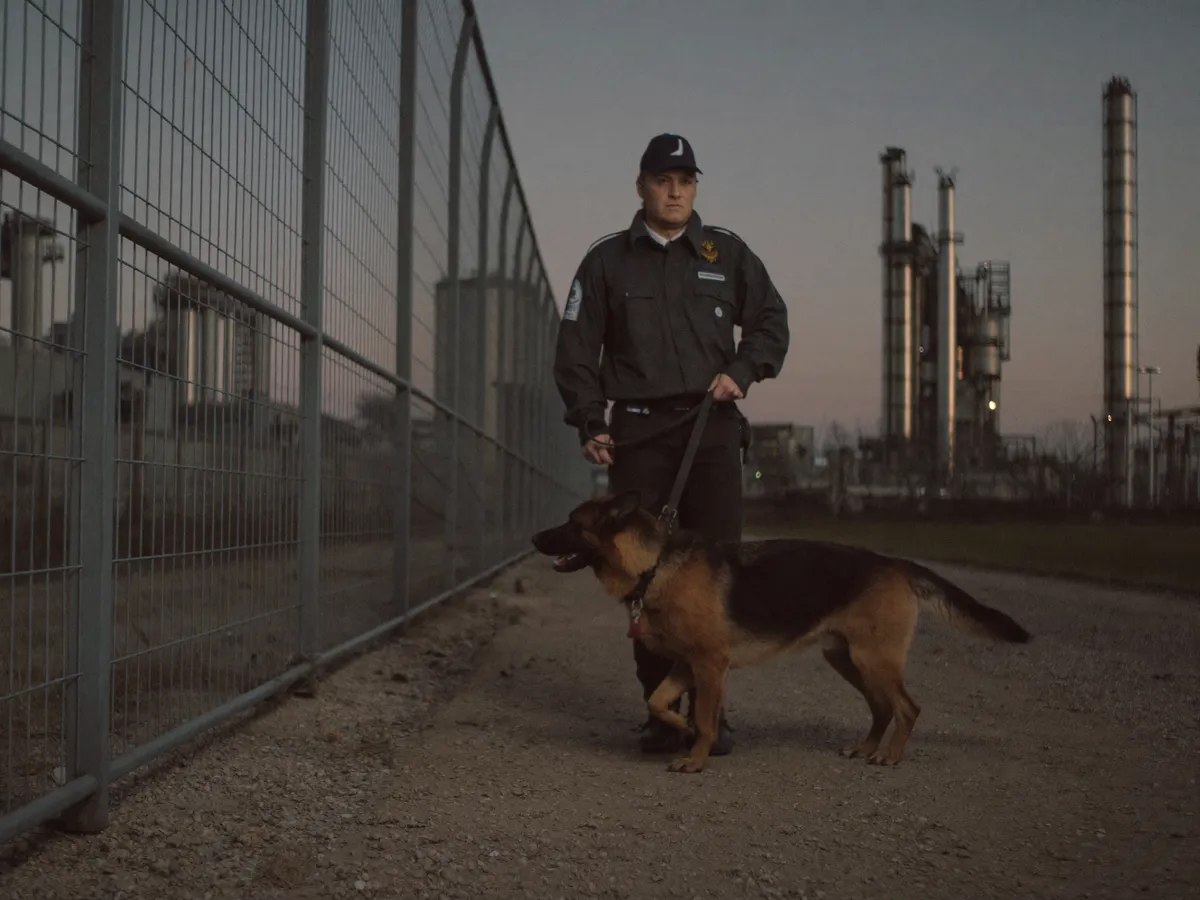 Hundeführer mit Diensthund bei der Bestreifung einer Baustelle in der Abenddämmerung